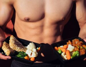 topless man in black shorts holding cooked food